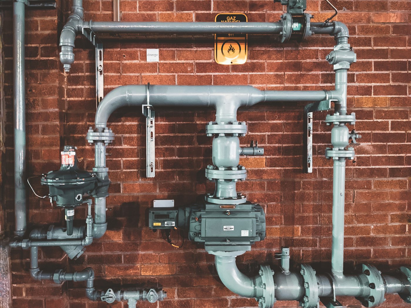 Industrial piping on a brick wall